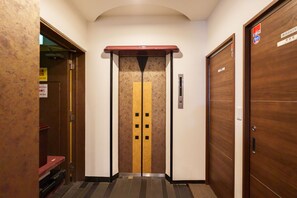 Een lift met een gele streep en zwarte vierkanten, met aan weerszijden houten deuren en een bord erboven.