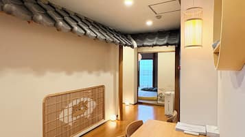 A traditional Japanese room with tatami flooring, a shoji screen, a low wooden table, and a sliding door leading to a bedroom.