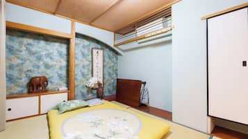 A traditional Japanese-style bedroom with tatami flooring, a futon bed, a shoji screen, and a sliding door.