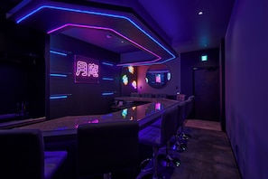 A bar area with neon signage, a long counter, and bar stools. - Tsukian (Osaka)