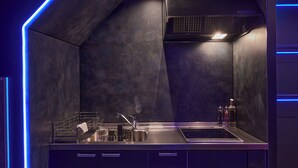 Uma cozinha moderna com bancada de aço inoxidável, forno embutido e coifa.