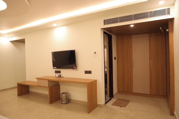 A modern room with a wooden desk, a television, and a wardrobe.