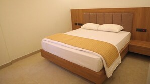 A single bed with a wooden headboard and a white mattress, accompanied by a wooden nightstand.