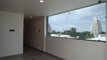 A corridor with a large window overlooking a temple and surrounding buildings.