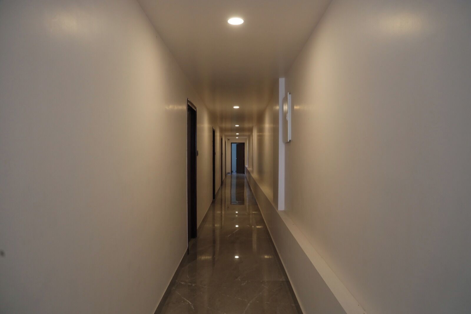 A long, narrow hallway with a shiny floor and recessed lighting.