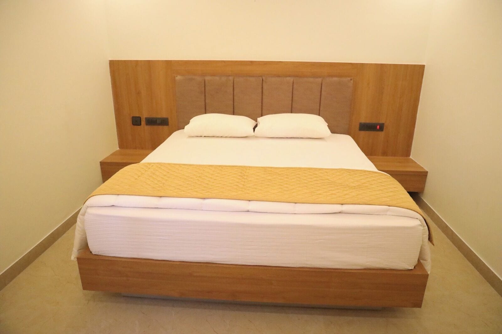 A single bed with a wooden headboard and two bedside tables, each with a lamp.
