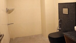 A bathroom with a black sink, a mirror, and a shower area.