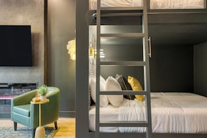 A room with a bunk bed, a green armchair, a small table with a plant, and a flat-screen TV. - East Nashville 4-Home Buyout With Rooftop, Sleeps 33 (Nashville)