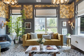 A cozy living room with a sofa, a coffee table with snacks, and a large window with a view of the outside. - East Nashville 4-Home Buyout With Rooftop, Sleeps 33 (Nashville)