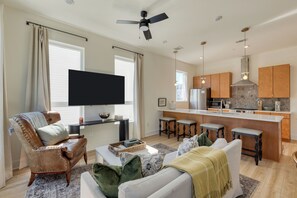 Una sala de estar moderna con un sofá, un sillón y un televisor de pantalla plana.