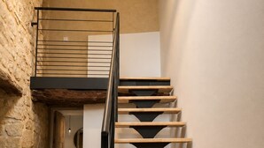 A staircase with wooden steps and a metal railing, leading to a landing with a light fixture above. - Stone house with a pool just outside Uzès (Garrigues-Sainte-Eulalie)