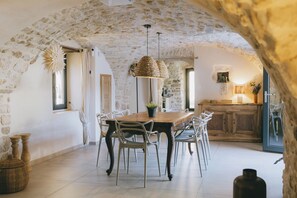 A rustic dining area with a stone arch, a wooden table, and metal chairs. - Stone house with a pool just outside Uzès (Garrigues-Sainte-Eulalie)