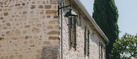 Ein Steinhaus im traditionellen Baustil, mit einem Hauseingang an der Ecke und einem sichtbaren Fenster.