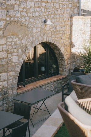 A stone wall with a window and a table and chairs in front. - Stone house with a pool just outside Uzès (Garrigues-Sainte-Eulalie)