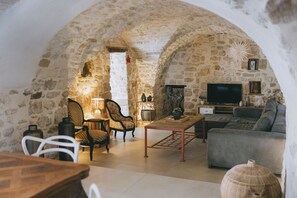 A rustic stone interior with a sofa, chairs, a TV, and a lamp. - Stone house with a pool just outside Uzès (Garrigues-Sainte-Eulalie)