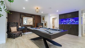 Een pooltafel met een modern design, een grote spiegel en een vissenkom in de ruimte.