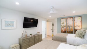 Een slaapkamer met een bed, een dressoir, een televisie en kunstwerken aan de wanden.