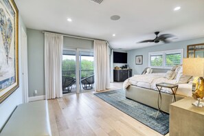 A bedroom with a bed, a desk, a chair, a ceiling fan, and a view of the outdoors. - Boater’s Paradise – 60’ Slip & No Fixed Bridges (Boca Raton)