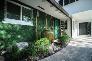 A modern house with a green wall, a large vase, and a stone pathway. - Boater’s Paradise – 60’ Slip & No Fixed Bridges (Boca Raton)