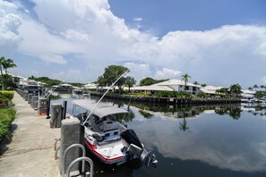 A marina with boats docked, a clear sky, and a building with a white roof. - Boater’s Paradise – 60’ Slip & No Fixed Bridges (Boca Raton)