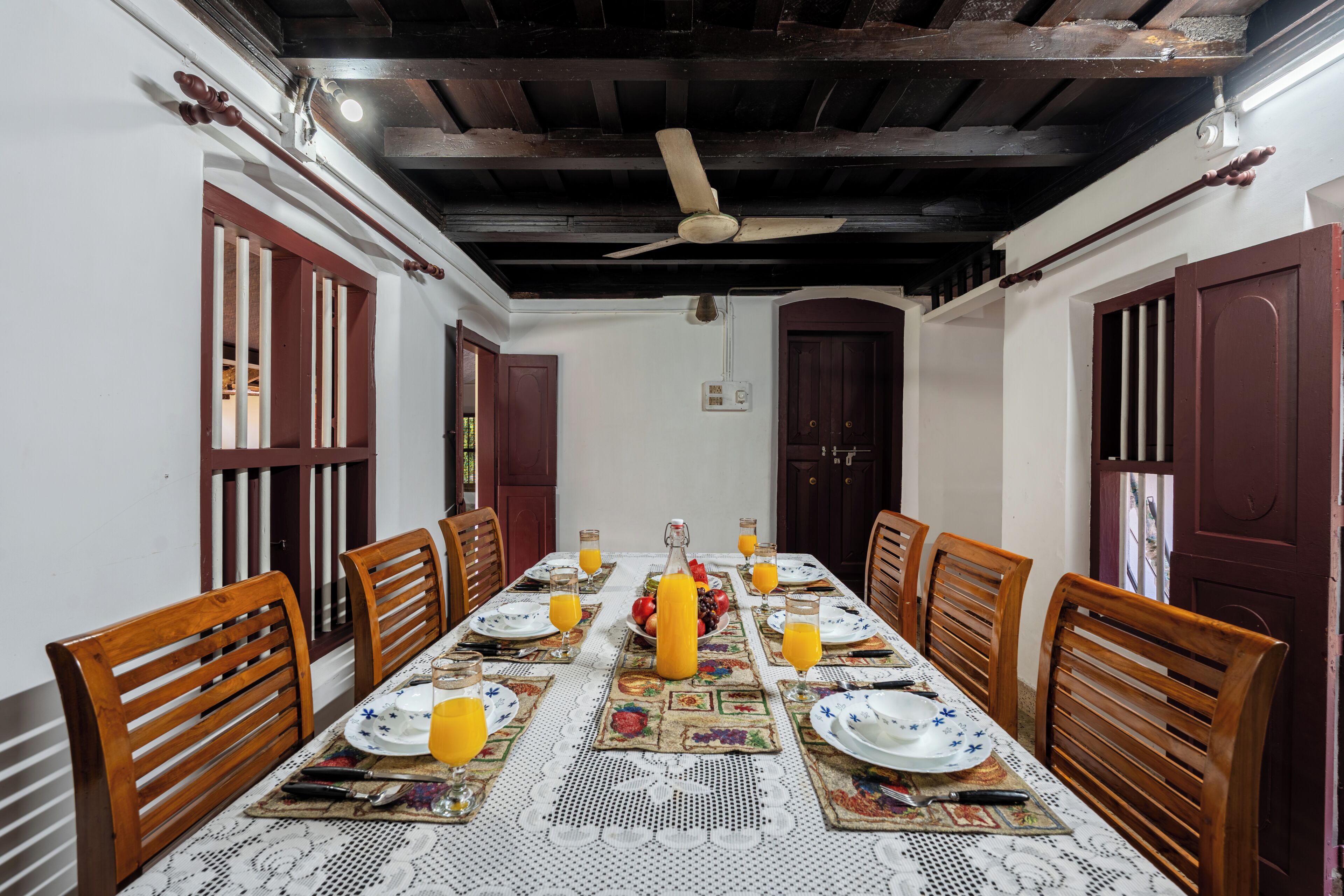 Comedor con una mesa larga dispuesta para seis personas, rodeada de sillas de madera.