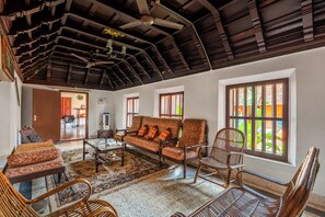 A spacious living room with a high ceiling, a sofa set, a coffee table, and a large window with a view.