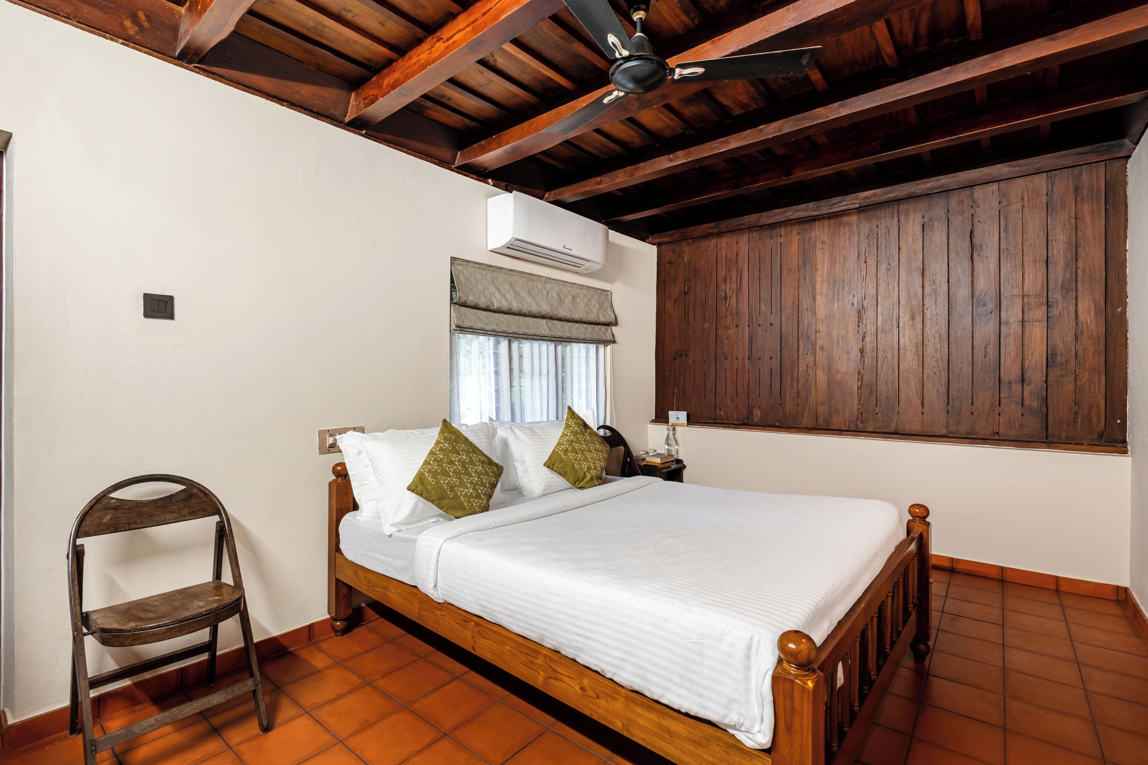 Un dormitorio con una cama de madera, una silla, una mesita de noche y un ventilador de techo.