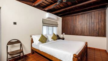 Un dormitorio con una cama de madera, una silla, una mesita de noche y un ventilador de techo.