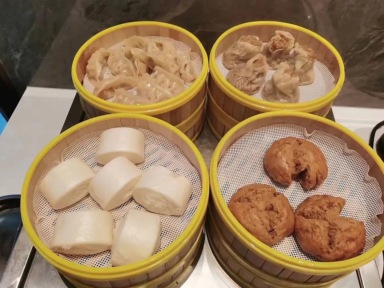 Cuatro vaporeras de bambú con alimentos.