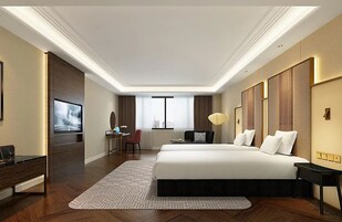 Una habitación de hotel con una cama grande, un escritorio con una silla, un televisor y una ventana con cortinas.