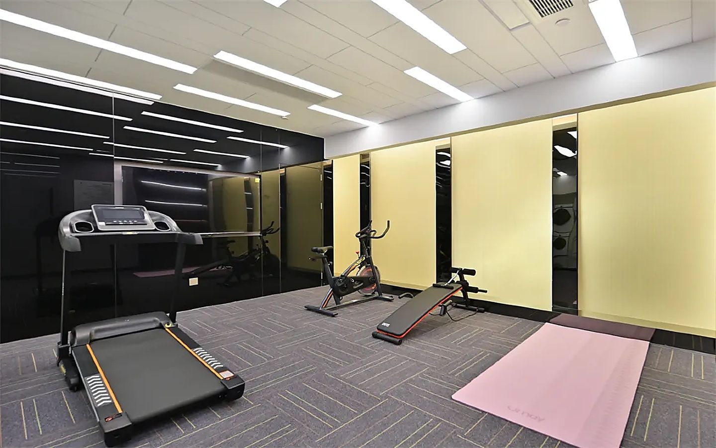 Ein Fitnessraum mit Laufband, Ergometer und einer Bank.