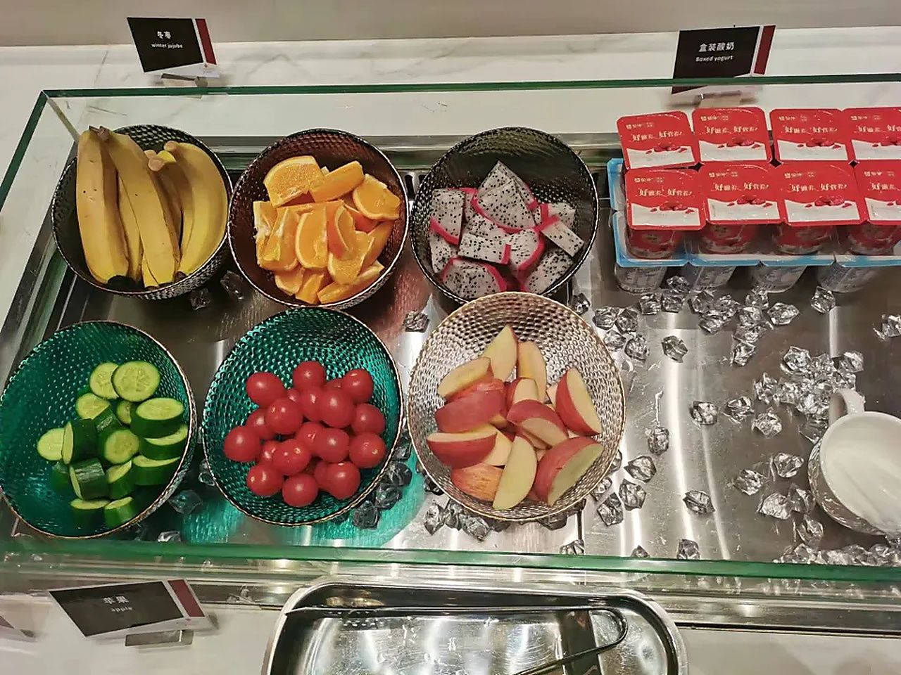 Un bufé con diversas frutas y una selección de yogures.