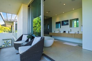 Een moderne badkamer met een ruime ligbad, een losstaand wastafelmeubel en een douchecabine met glazen wanden.