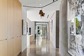 A modern hallway with a wooden panel wall, a reception desk, and a large window with a view of greenery.