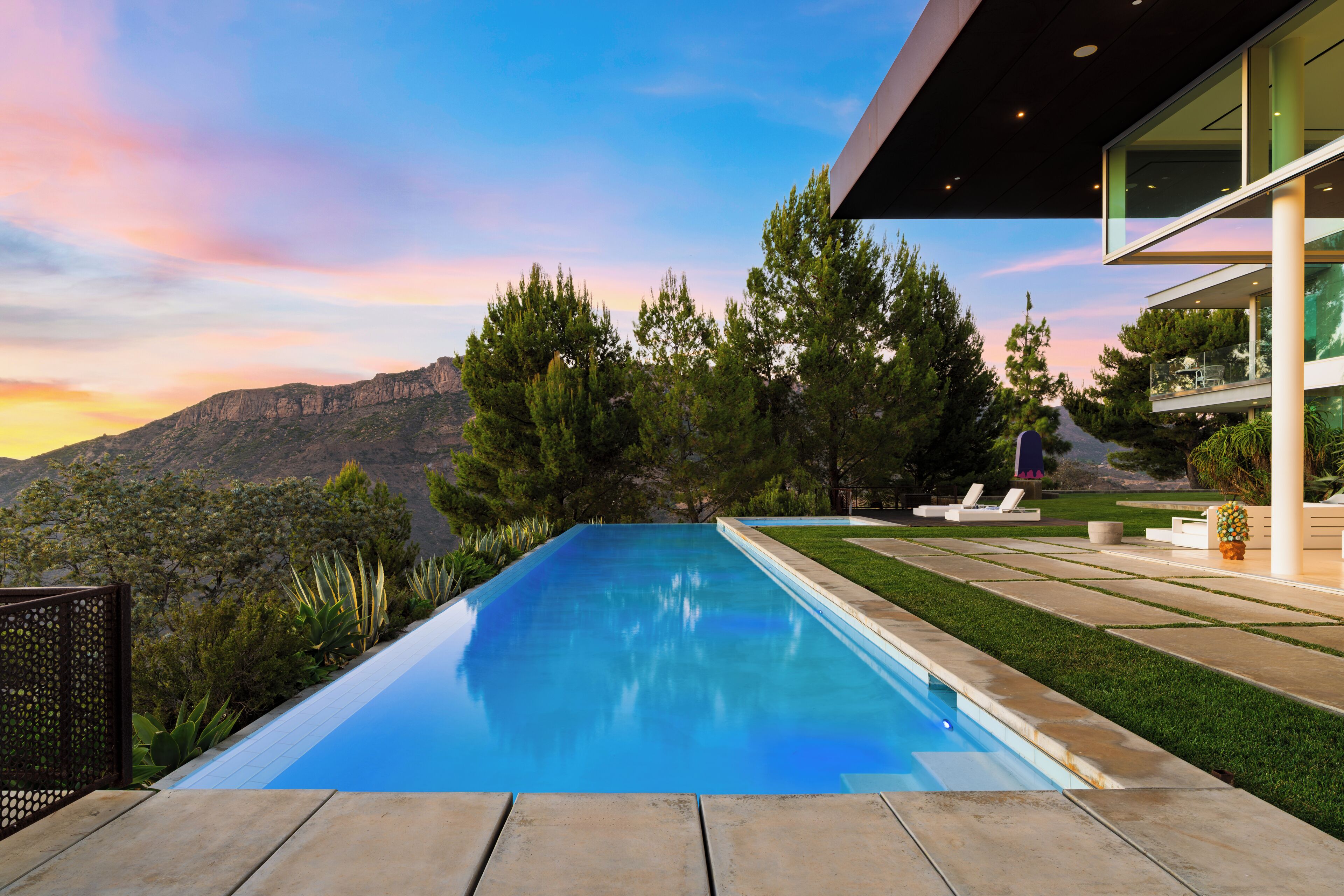 Una piscina moderna amb una vista clara de muntanyes al fons.