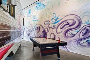 A foosball table in a hallway with a mural on the wall. - Art Gallery + Infinity Pool + Theater | Ocean Views | The Malibu Art Estate (Malibu)