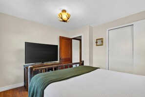 A bedroom with a bed, a television on a wooden stand, a door, and a light fixture. - Firepit + Valley-View Deck | Creek + Valley Views + Slopes | Creekside Cabin (Lexington)