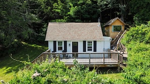 A small cabin with a deck, surrounded by dense greenery. - Firepit + Valley-View Deck | Creek + Valley Views + Slopes | Creekside Cabin (Lexington)