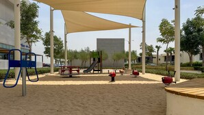 A playground with sand, a slide, and swings. - Elegant Studio Retreat in Damac Hills (Dubai)