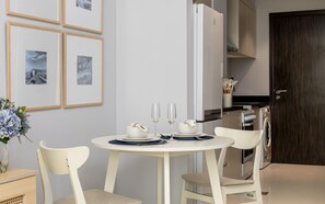 A dining area with a round table, chairs, and a vase of flowers. - Elegant Studio Retreat in Damac Hills (Dubai)