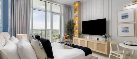 A modern living room with a sofa, a dining table, and a TV mounted on the wall.