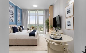 A modern hotel room with a large bed, a dining area, and a TV. - Elegant Studio Retreat in Damac Hills (Dubai)