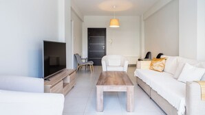 Ein modernes Wohnzimmer mit einem Flachbildfernseher, einem Holztisch, einem weißen Sofa und einem Sessel.