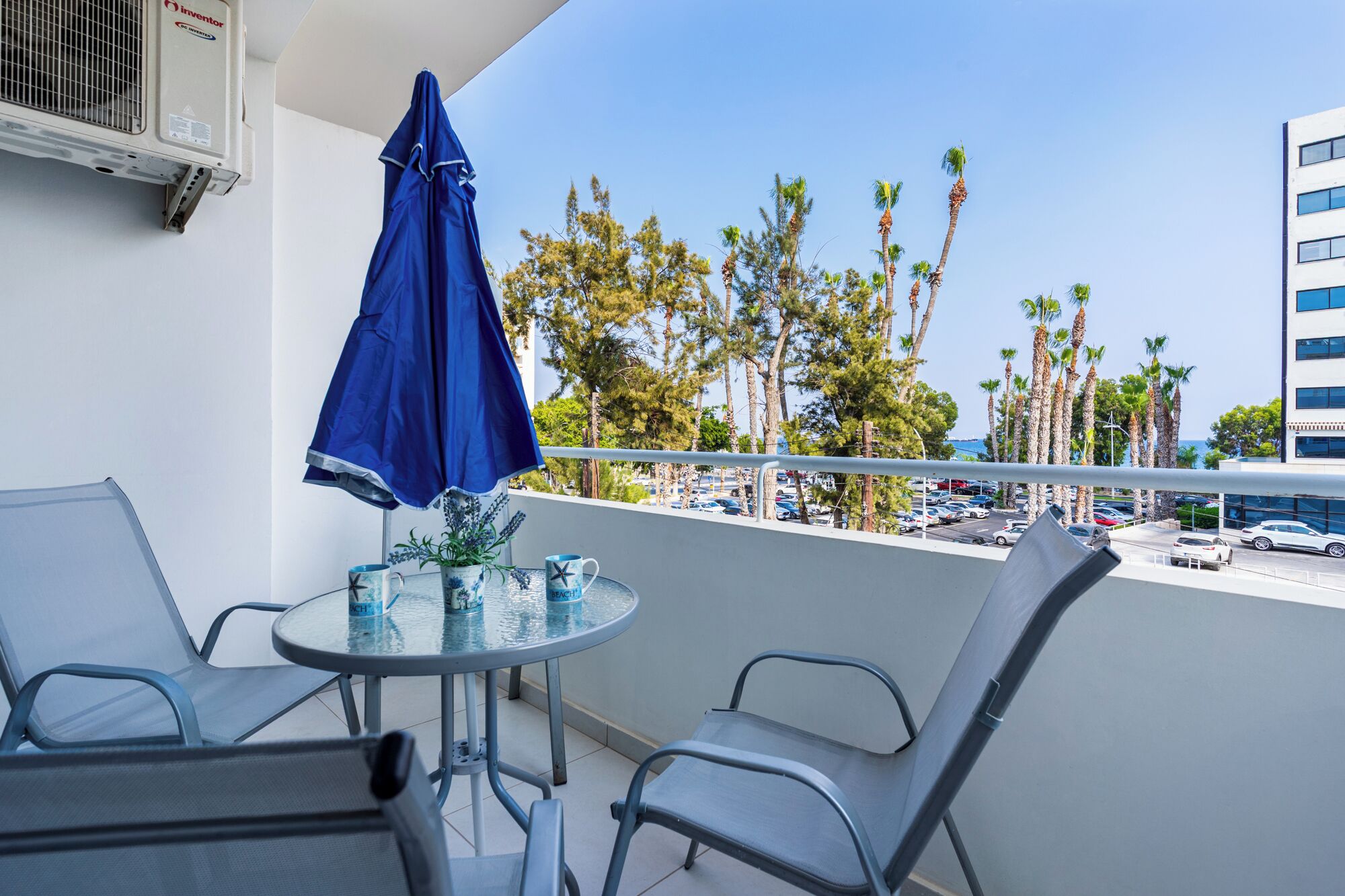 A balcony with a table, chairs, and a blue umbrella.