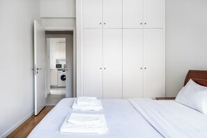 Un dormitorio con una cama, toallas blancas, un cabecero de madera y un armario.