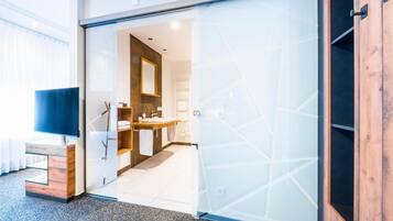 Un baño moderno con mampara de vidrio, tocador de madera y espejo.