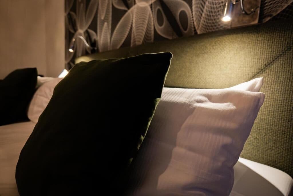 Un letto con una testiera verde e dei cuscini.