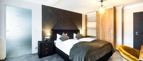 Ein modernes Schlafzimmer mit einem großen Bett, Nachttischen, einem Holzschrank und einem außergewöhnlichen gelben Sessel.