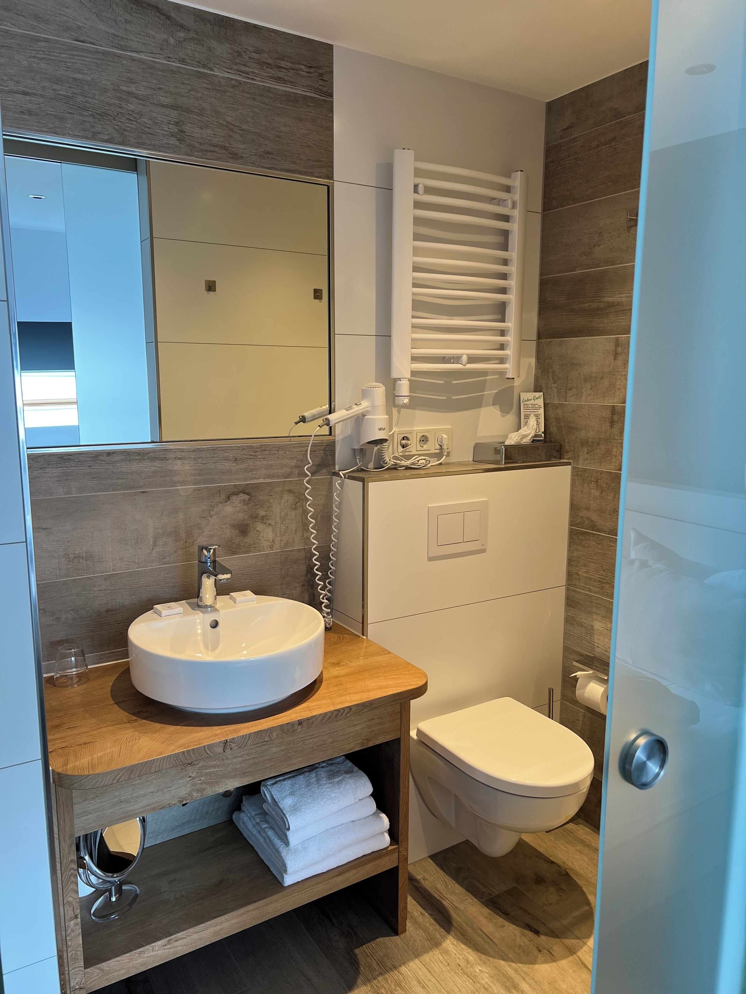 Ein modernes Badezimmer mit einem runden Waschbecken, einer Toilette und einem Handtuchhalter.