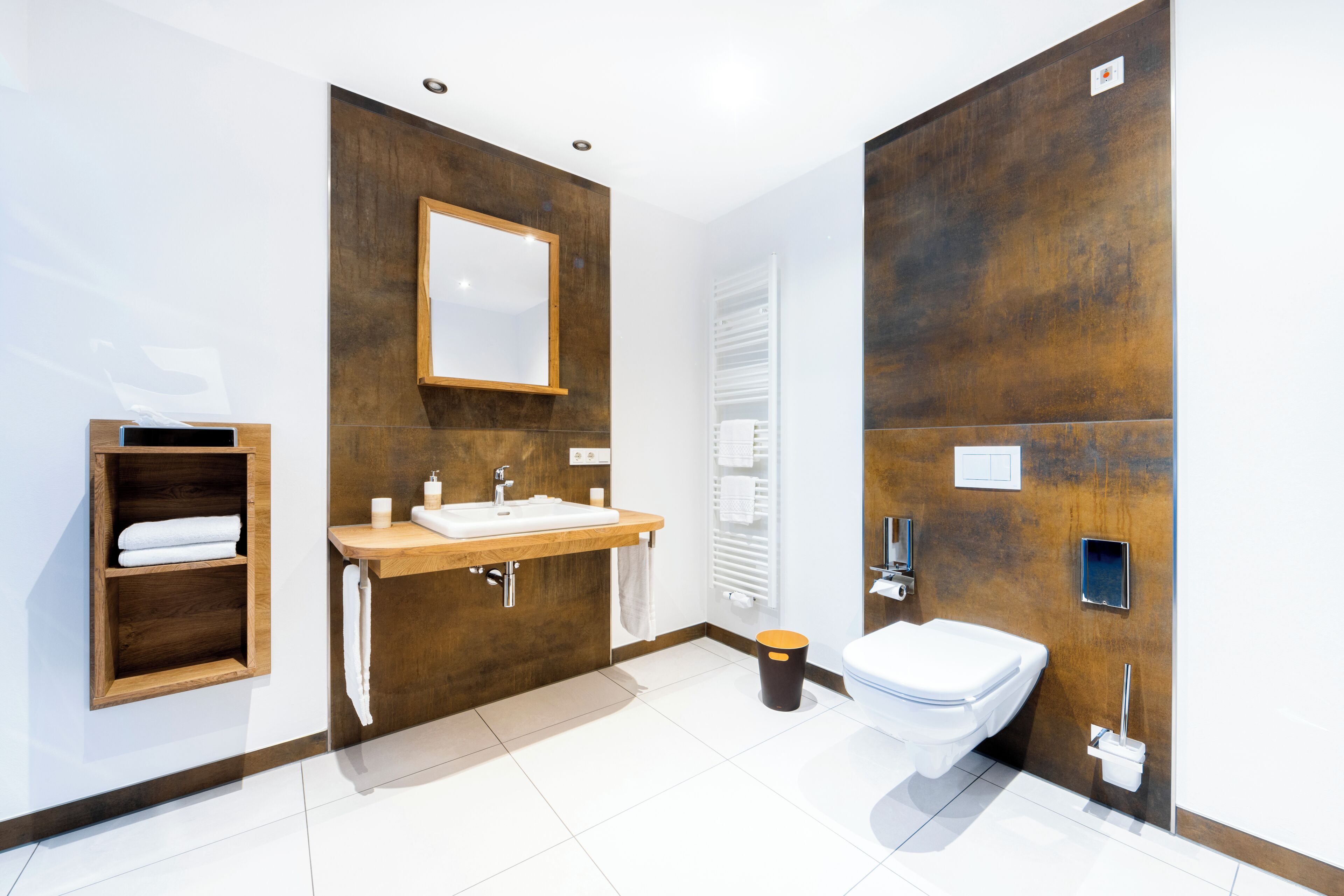 A modern bathroom with a wooden vanity, a large mirror, a white sink, and a toilet.